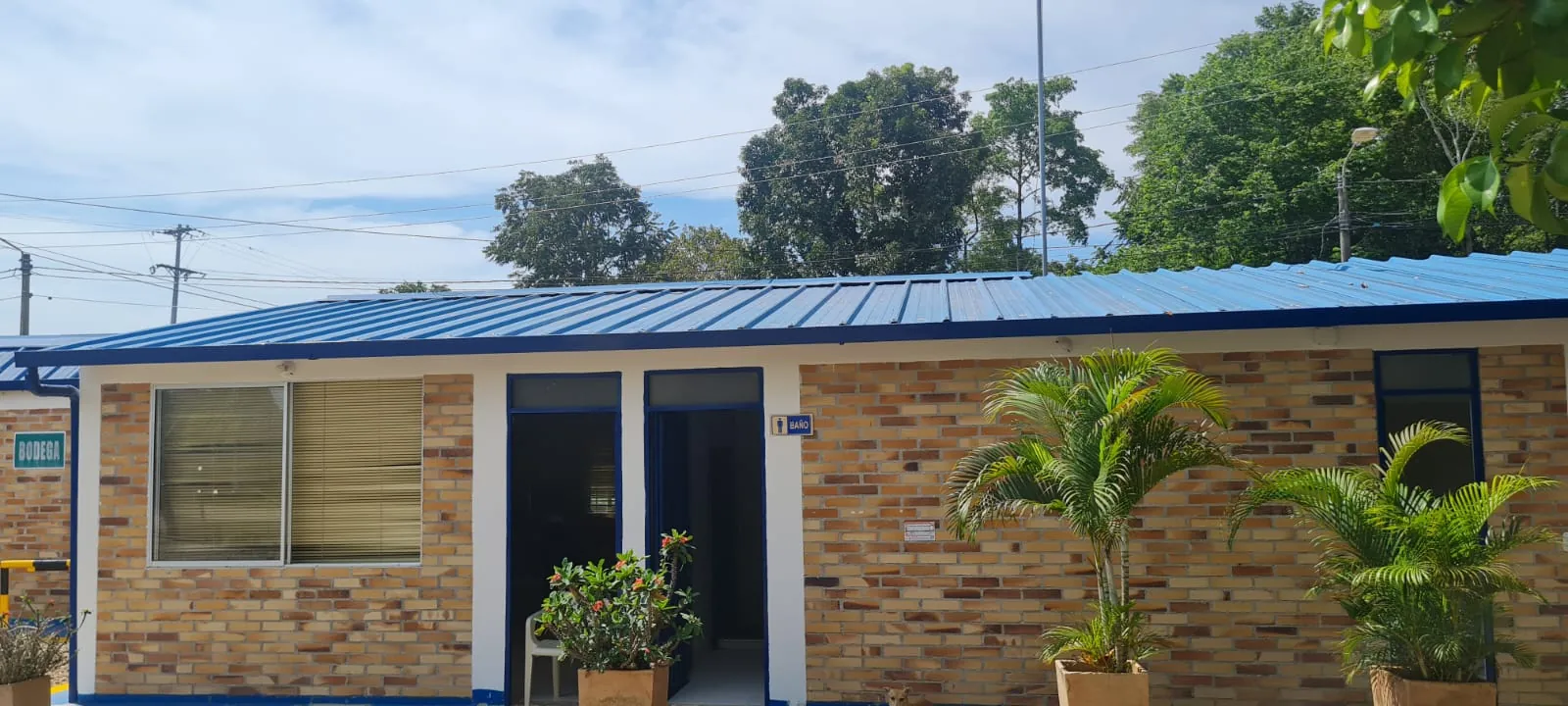 Fachada de oficinas y baños con ventanería y cubierta metálica azul