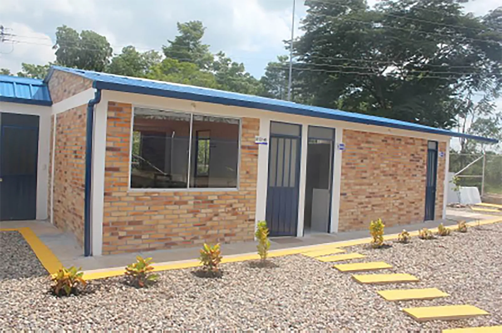 Fachada del bloque administrativo en ladrillo a la vista con ventanería metálica azul y senderos con demarcación amarilla