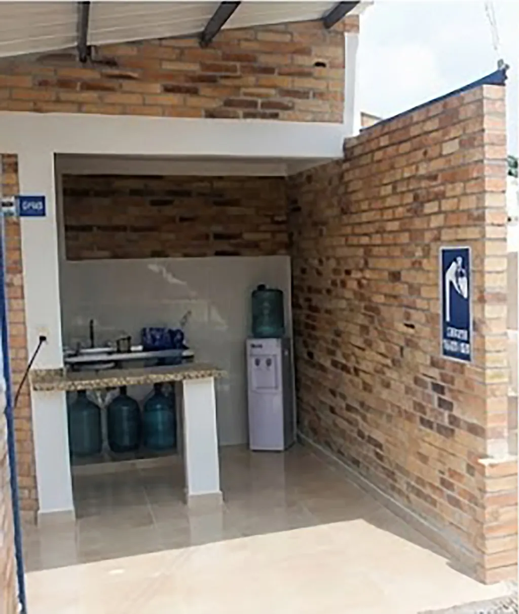Cafetería con mesón enchapado, dispensadores de agua y nevera