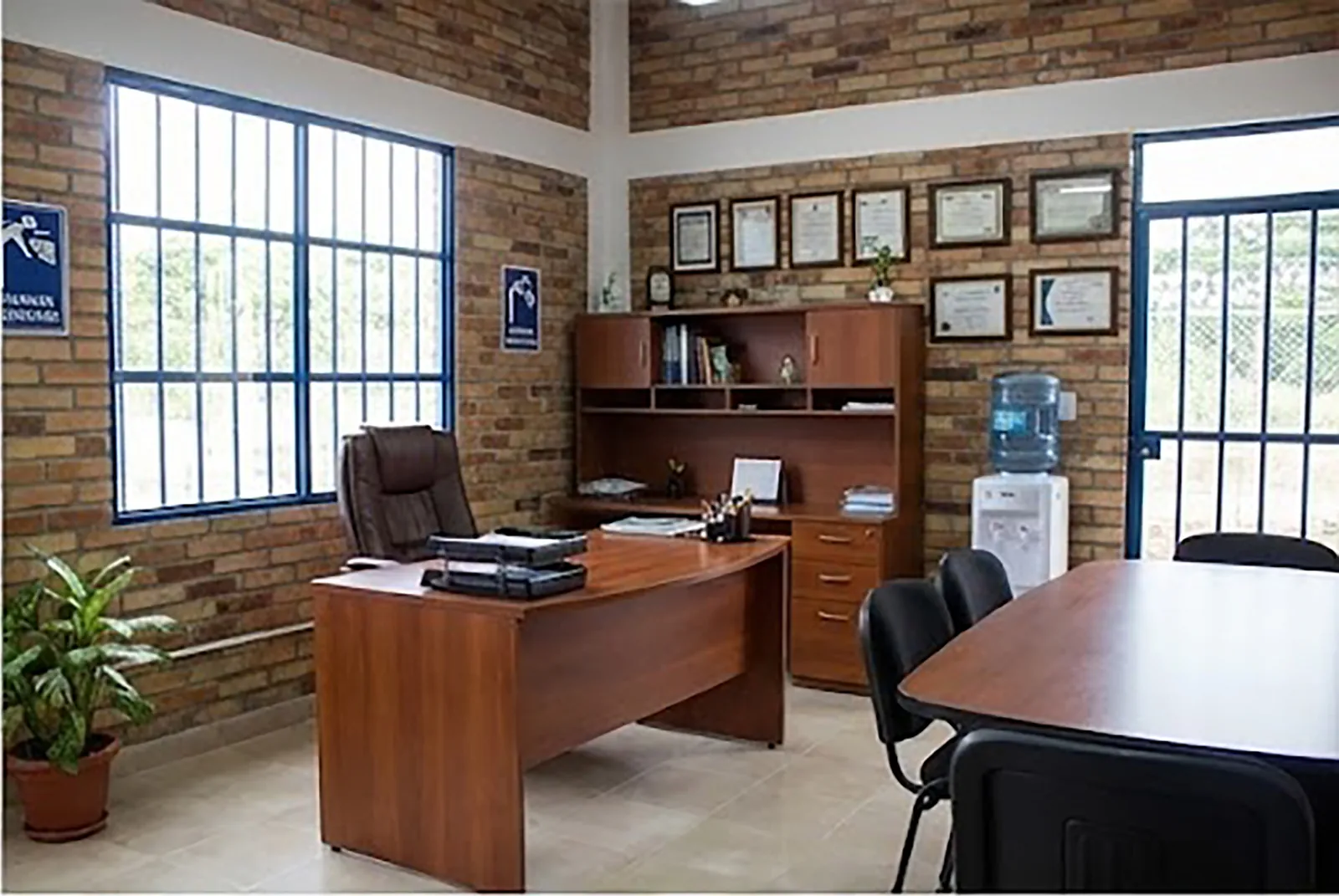 Oficina de gerencia con escritorio en madera, biblioteca, certificaciones enmarcadas y mesa de reuniones