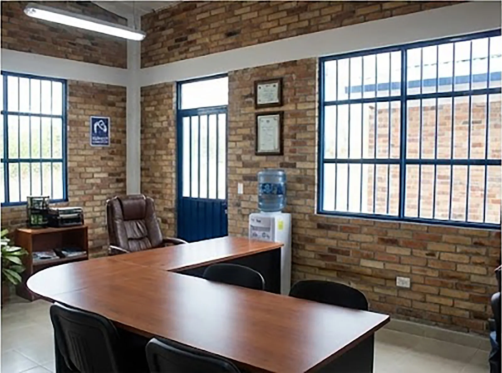 Sala de reuniones con mesa en L, ventanales y muros en ladrillo a la vista